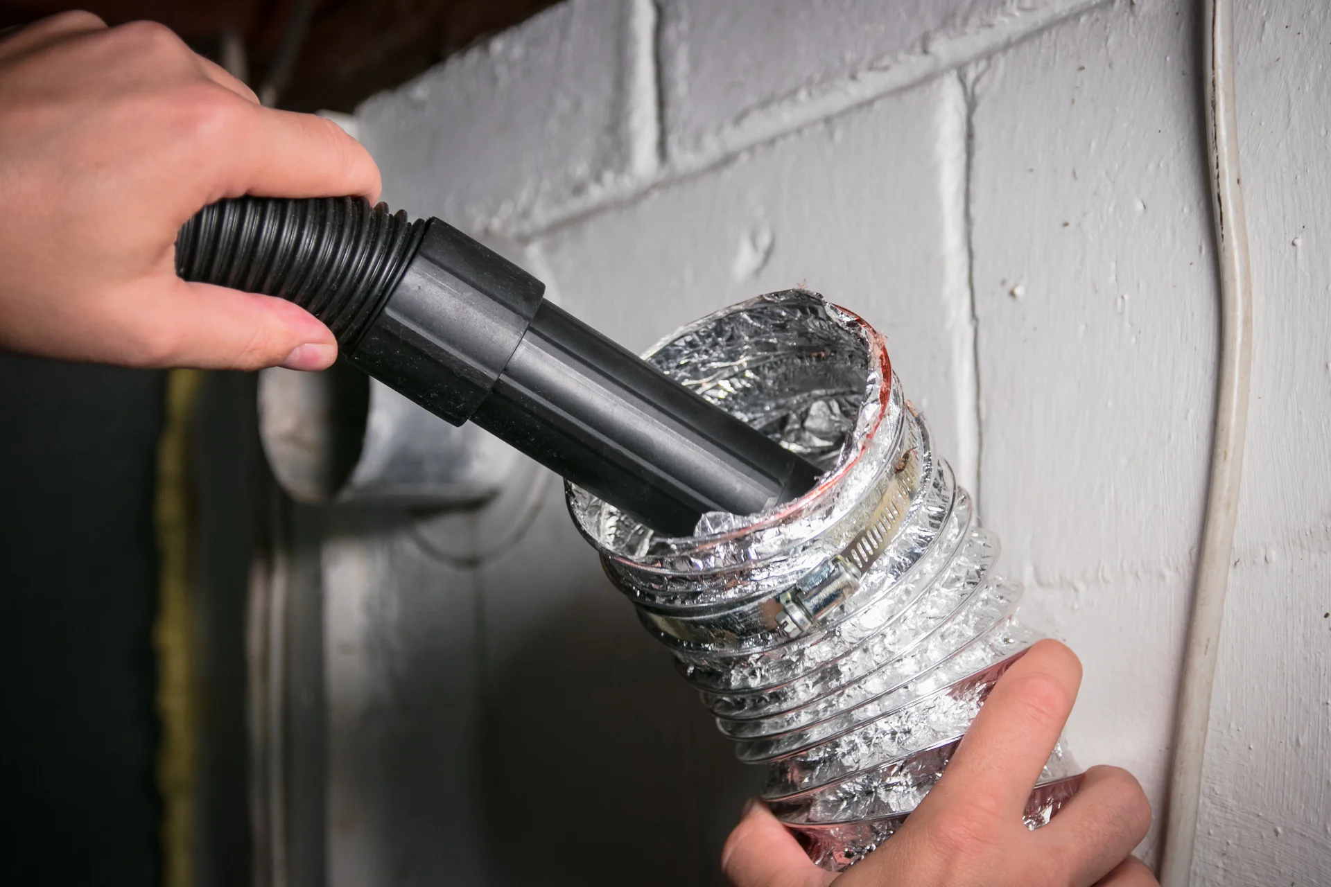 Worker doing air duct cleaning with black vacuum